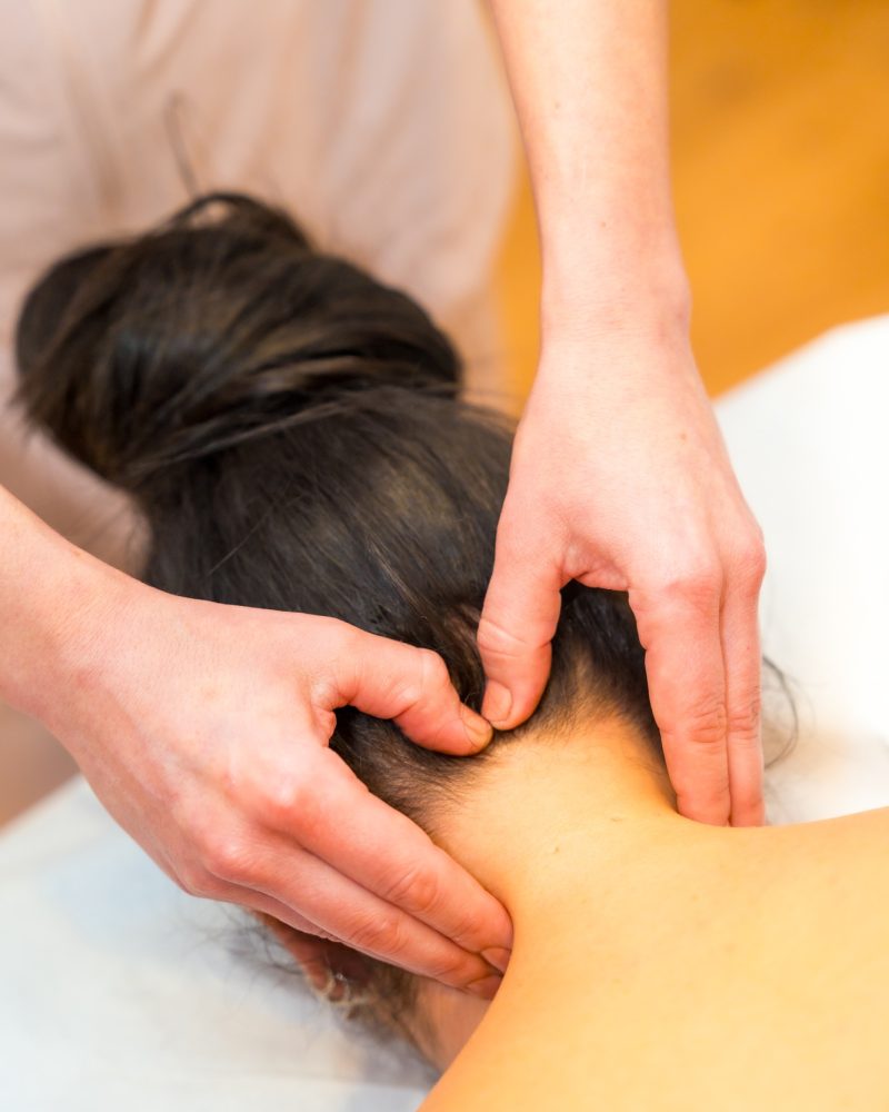 Masseur giving a neck massage to a relaxed woman